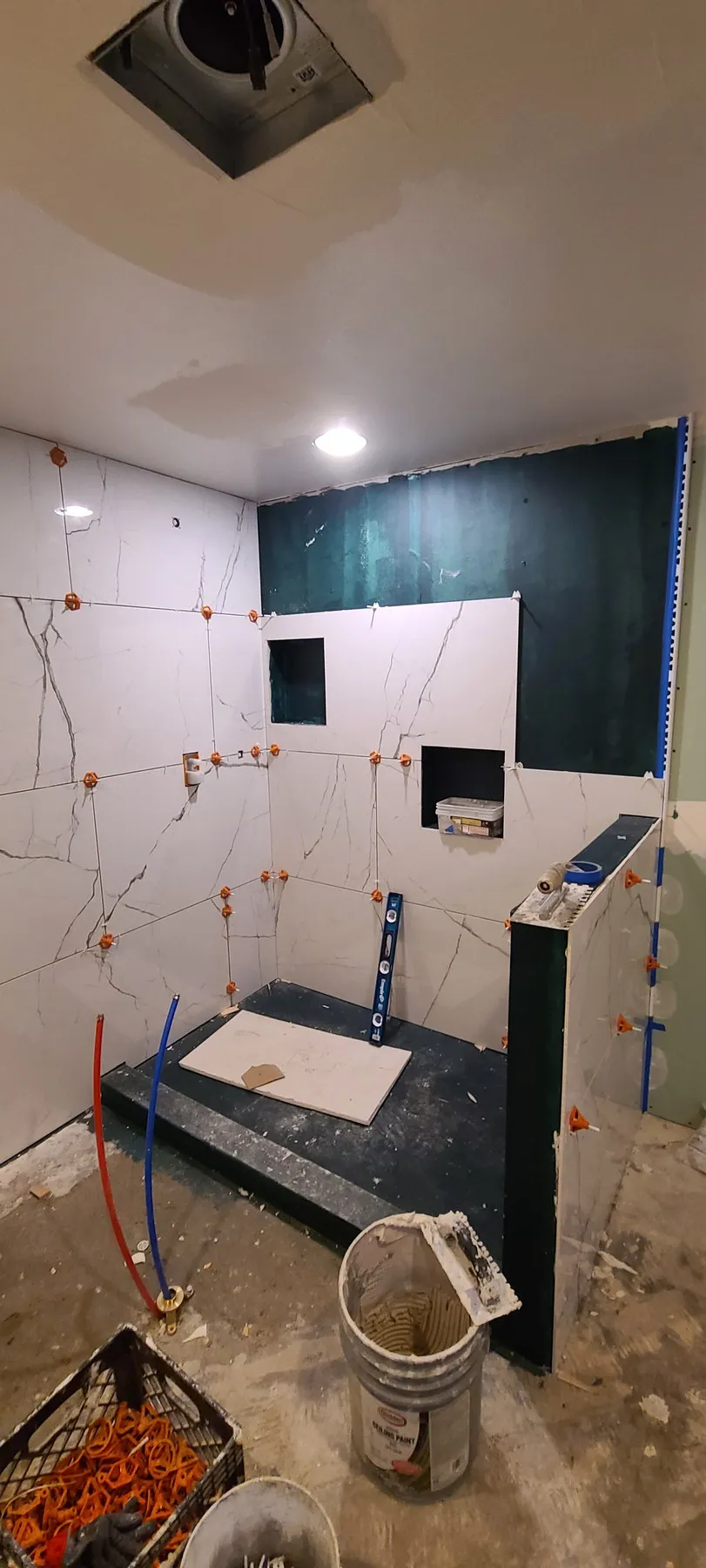 Before — tiling going up, then glass shower and black marble floor — Renton