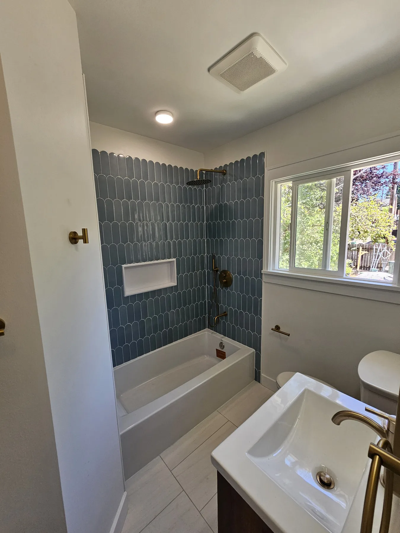 A tiled shower wall and niche in a finished bathroom