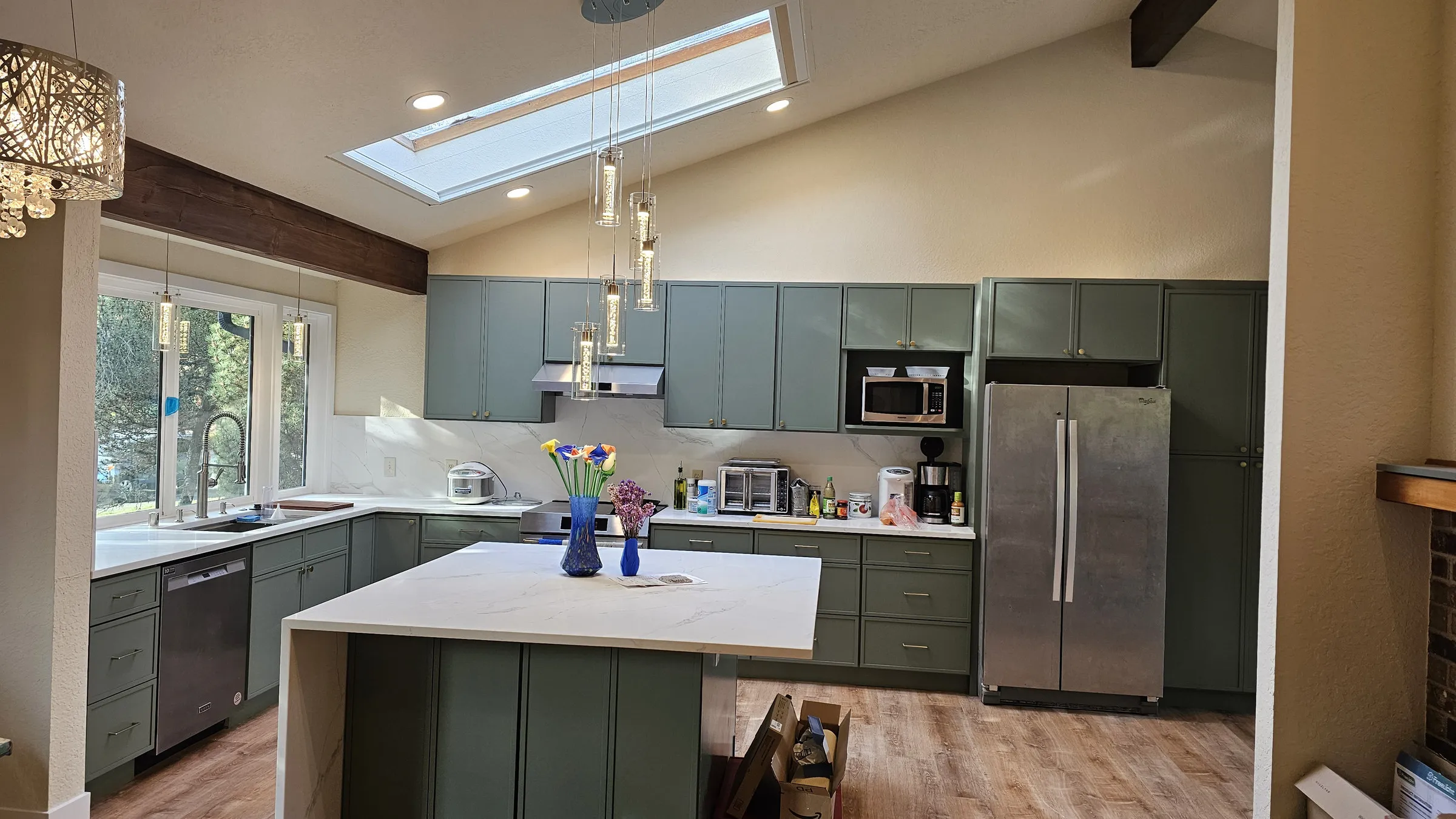 After — A galley kitchen before and after renovation, oak cabinets and parquet replaced with sage-green shaker, a quartz island and wood flooring
