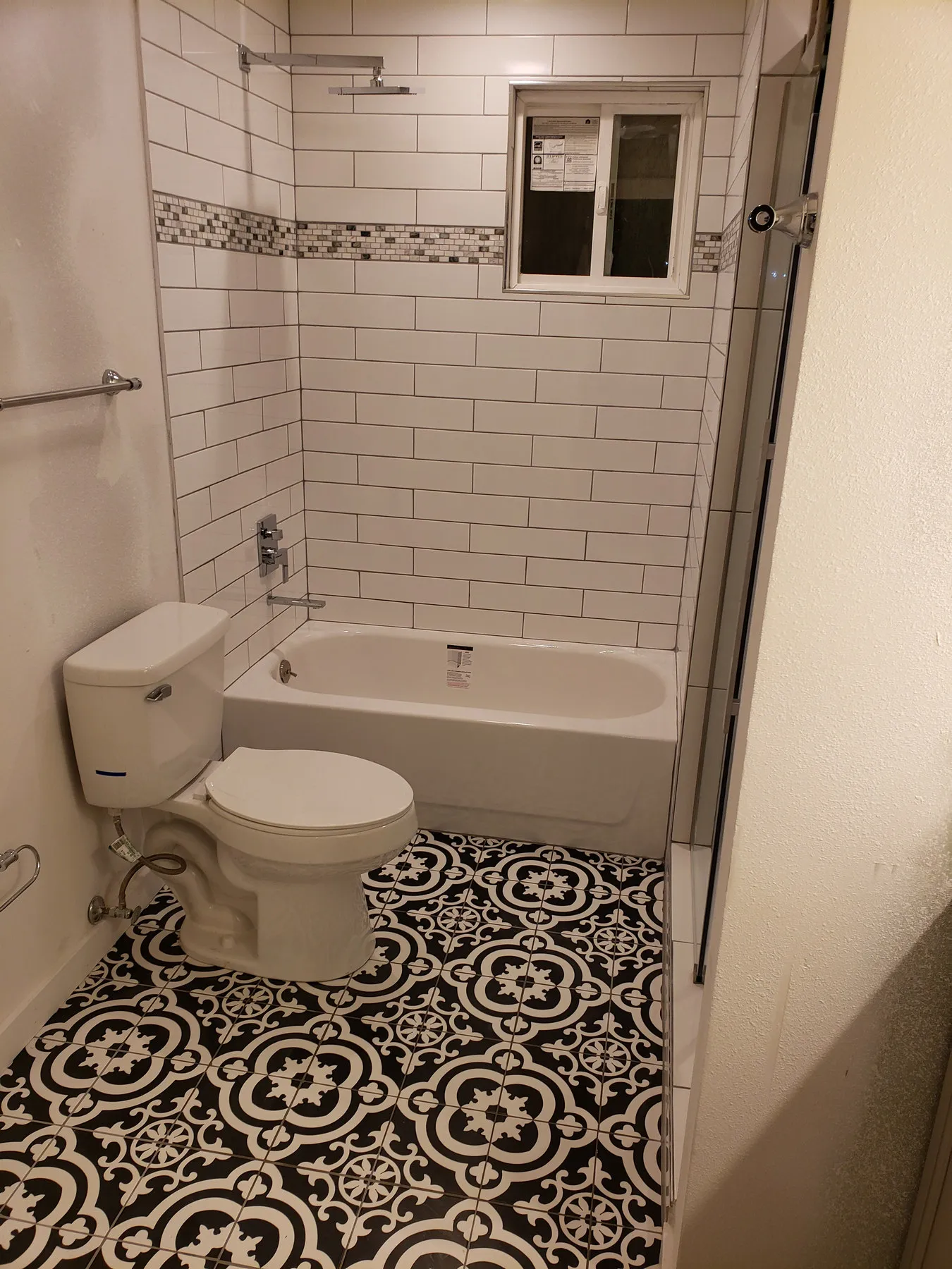 A bathroom with a patterned black and white cement tile floor