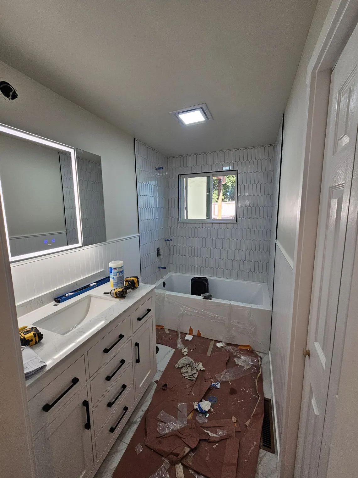 A new vanity set level and secured against the wall, the floor still back to subfloor around it