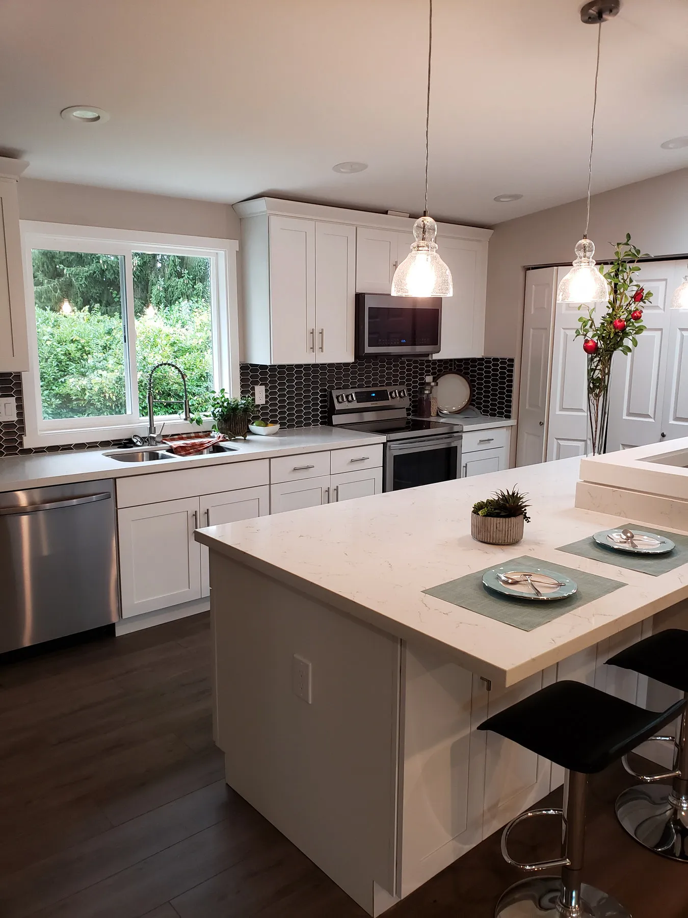 A finished white kitchen in Ballard, Seattle — shaker cabinets, a quartz island with stools and a mosaic tile backsplash