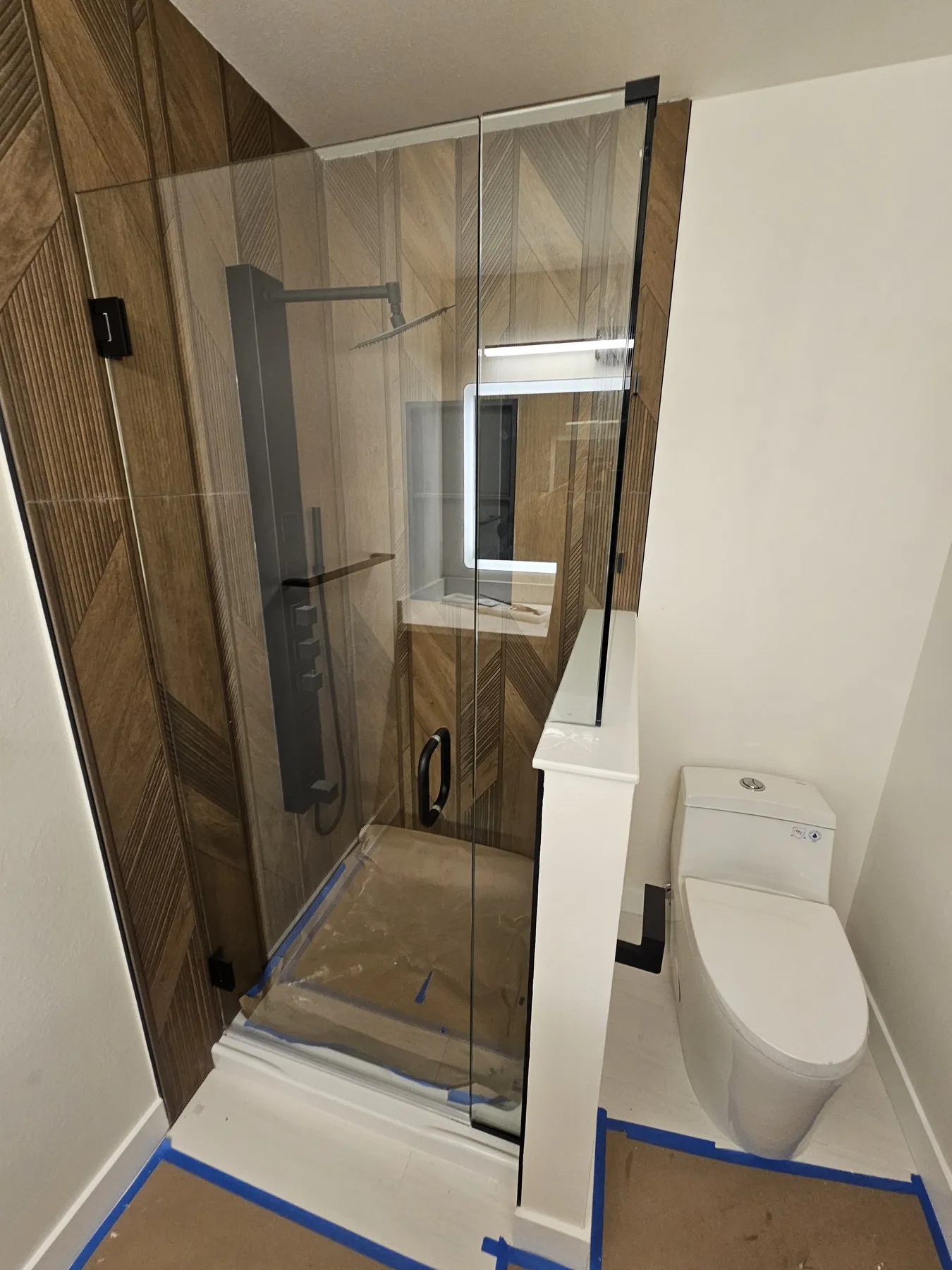A walk-in shower with a wood-panelled wall and frameless glass, First Hill, Seattle