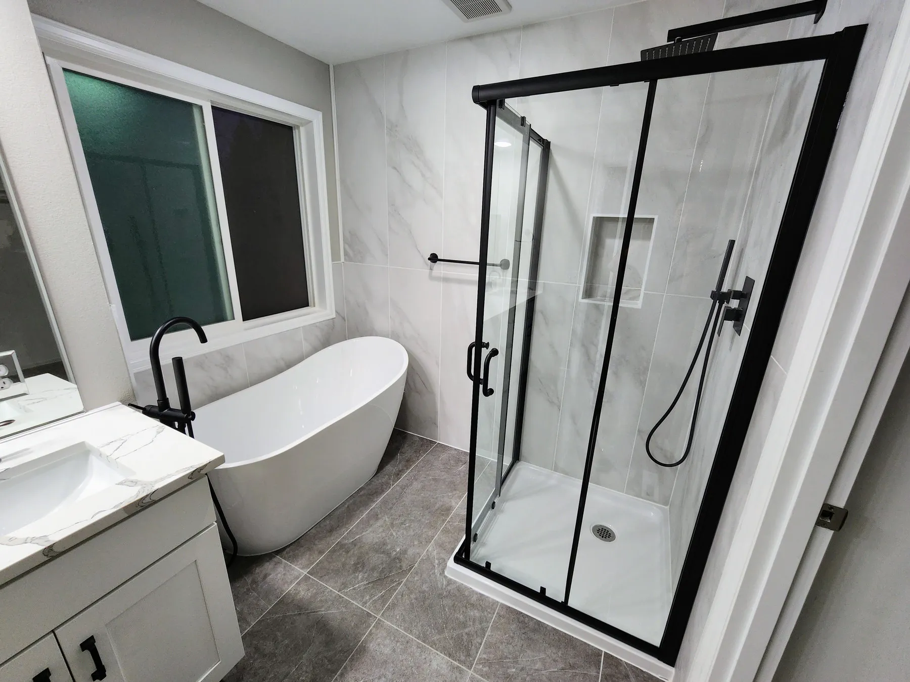 A finished bathroom in Overlake, Redmond — freestanding tub, black-framed glass shower and large-format grey tile
