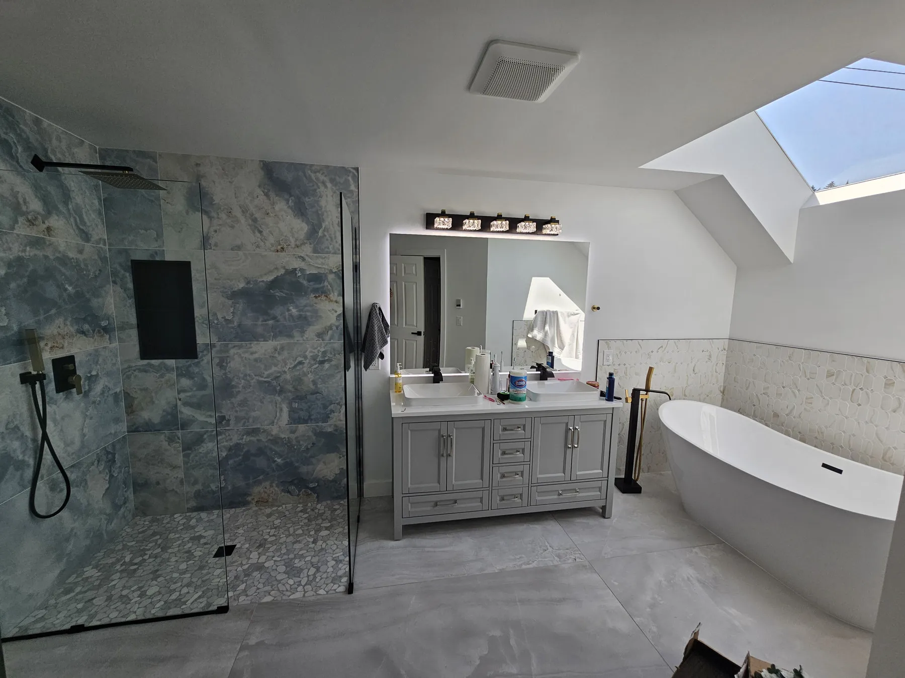 A Woodinville primary bathroom — blue marble shower, double vanity and a freestanding tub under a skylight