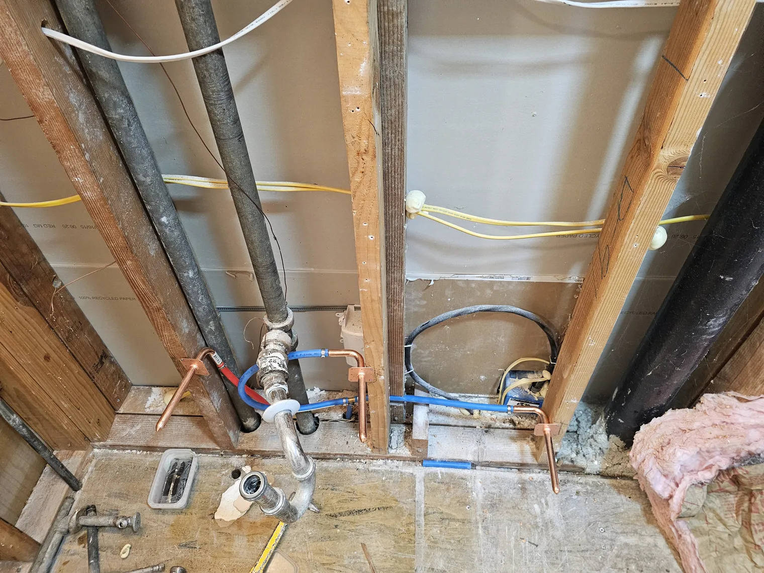 Supply lines and a shower valve roughed into an opened wall, repositioned for a shower where a tub used to sit